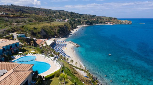 Spiaggia con acqua turchese e ombrelloni.