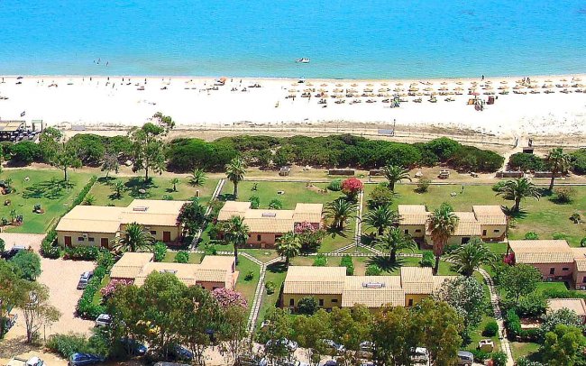 Spiaggia con ombrelloni e vialetti circondati da palme e bungalow.