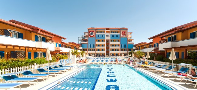 Piscina con lettini e edifici colorati.