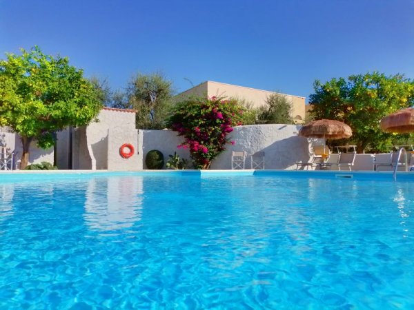 Piscina con fiori e ombrelloni di paglia.
