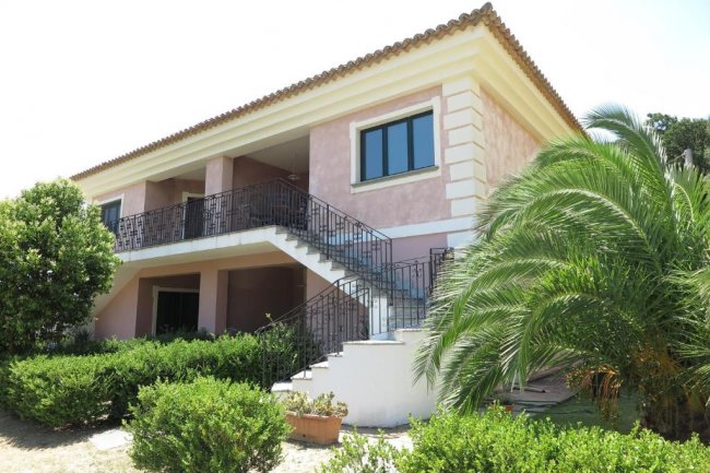 Casa rosa con scala esterna nera e palma.