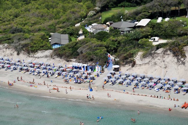 Spiaggia affollata con ombrelloni e bagnanti.
