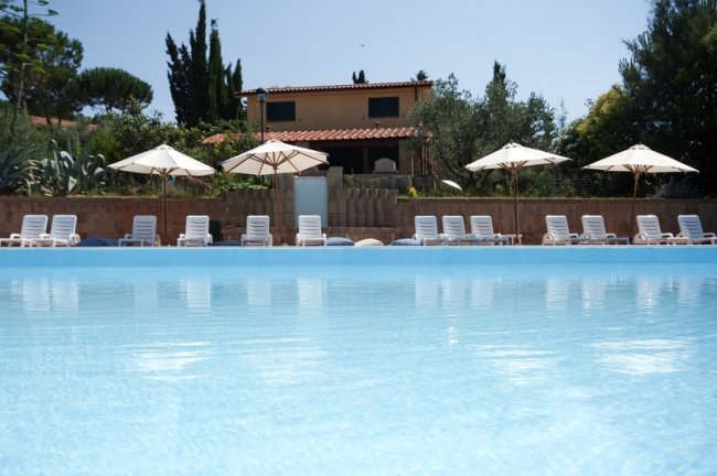Piscina con lettini e ombrelloni bianchi.