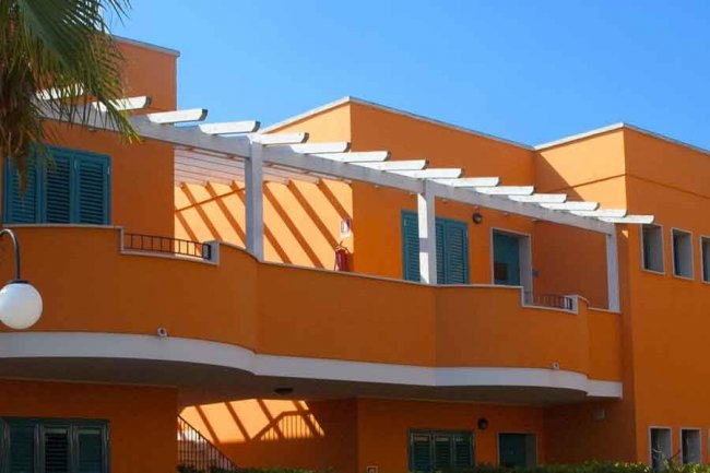 Edificio arancione con persiane verdi.