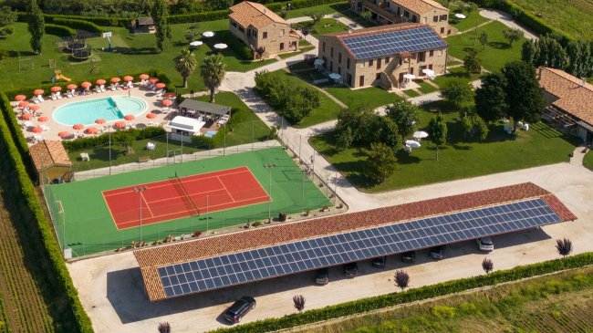 Vista aerea di complesso con piscina e campo da tennis.