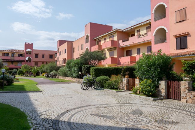 Complesso residenziale rosa con vialetto pavimentato.
