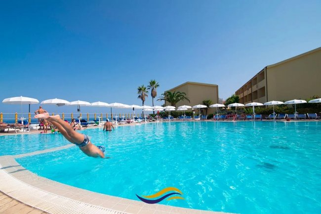 Tuffo in piscina con ombrelloni bianchi.