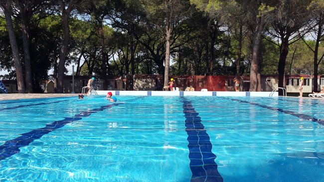 Piscina all'aperto con persone che nuotano.