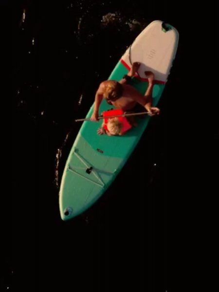 Persona rema con bambino su un paddleboard.
