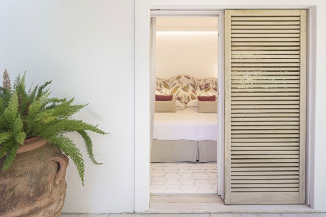 Porta aperta verso una camera da letto luminosa.