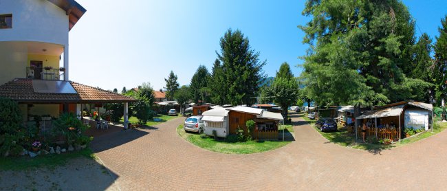 Area campeggio con roulotte e alberi verdi.
