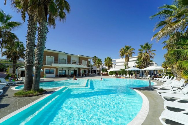 Piscina con sedie a sdraio e palme.