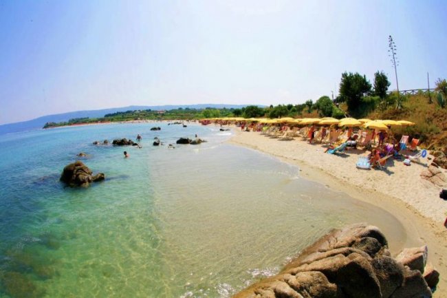 Spiaggia con ombrelloni gialli e acque chiare.