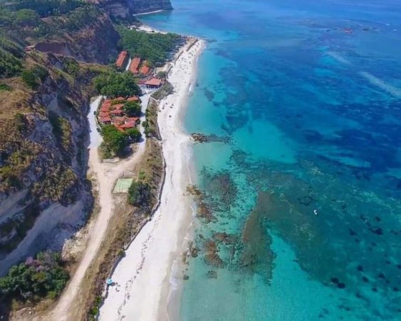 Costa rocciosa e mare turchese dall'alto.