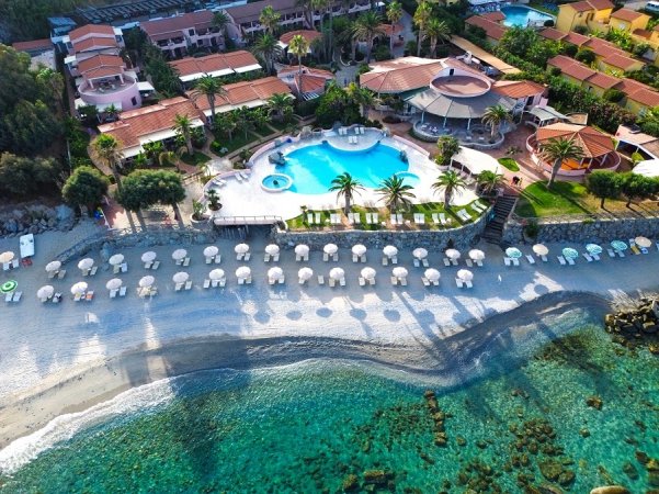Resort con piscina e ombrelloni sulla spiaggia vista dall'alto.