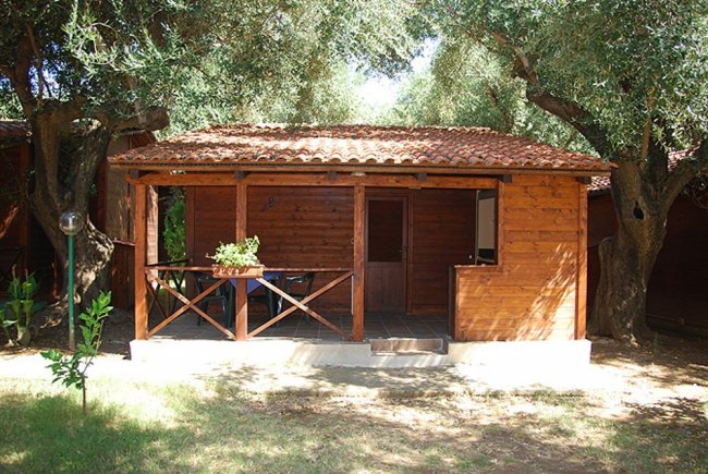 Casetta in legno con portico e giardino intorno.