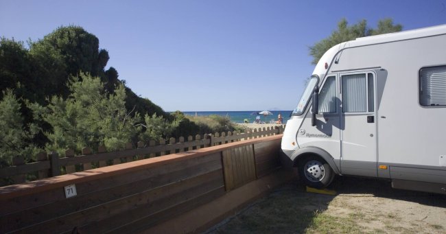 Camper parcheggiato accanto a una staccionata, vista mare.