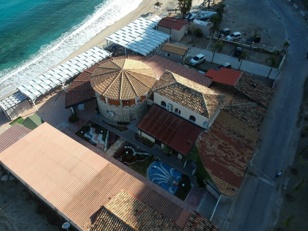 Complesso sul mare con tetti rossi e giardino.