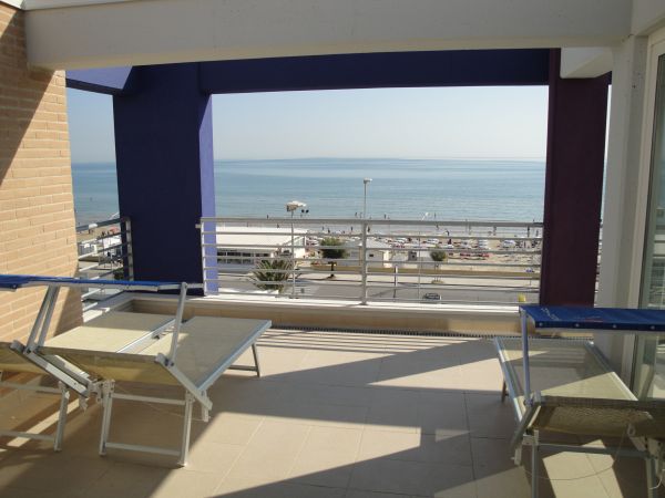 Terrazza con lettini e vista sul mare, oltre un corrimano.