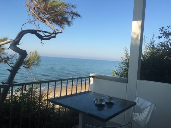 Tavolo con tazzine su balcone vista mare.