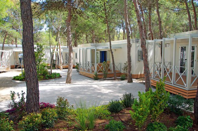 Bungalows tra gli alberi, con vialetti e giardino curato.