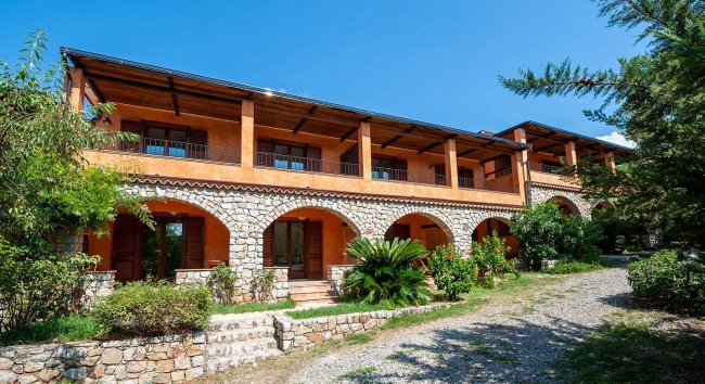 Edificio in pietra con arcate e ampie verande.