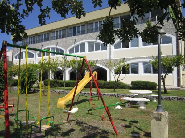 Altalena e scivolo davanti a un edificio.