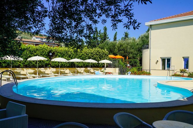 Piscina rotonda con lettini e ombrelloni bianchi.
