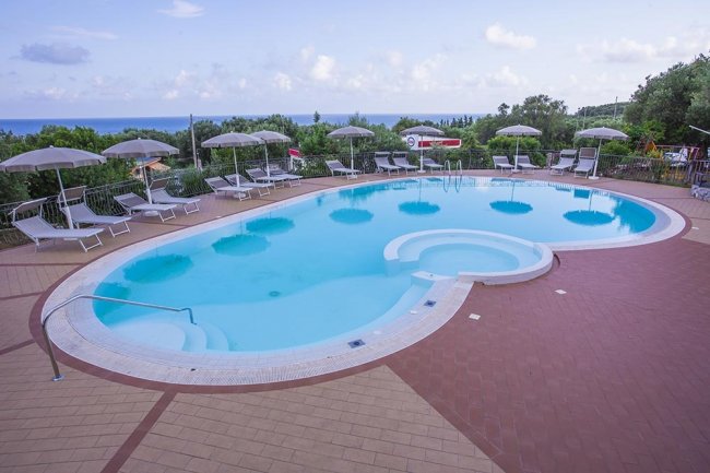 Piscina ovale con ombrelloni e vista sul mare.