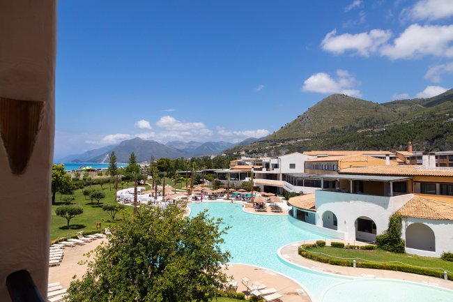 Piscina del resort circondata da verde e montagne.