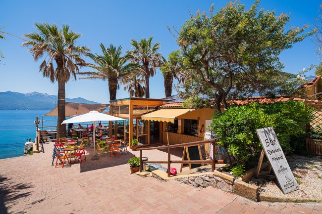 Ristorante all'aperto con ombrelloni colorati vicino al mare.