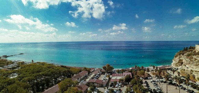 Vista mare con spiaggia, alberi e parcheggio.