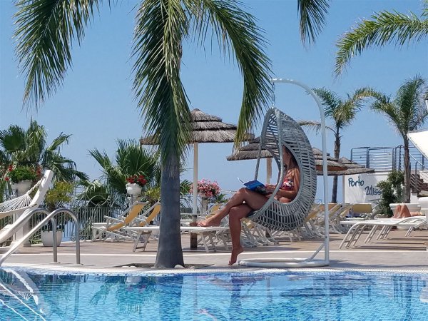 Persona su sedia sospesa accanto a piscina.