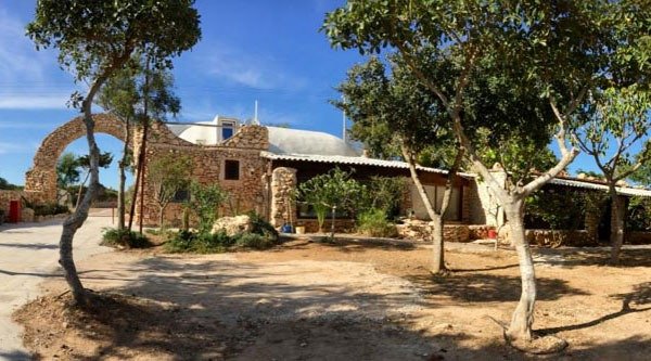 Casa rustica in pietra circondata da alberi.