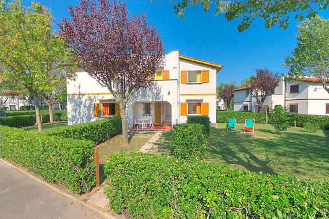 Casa con giardino e due sedie a sdraio.