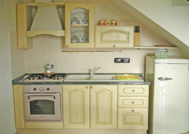Cucina compatta con mobili chiari e elettrodomestici.