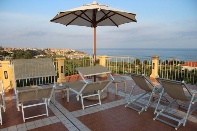 Terrazza con ombrelloni e lettini vista mare.