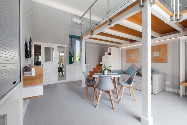 Interno moderno con soppalco e tavolo.