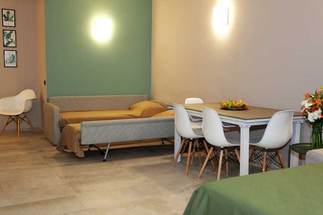 Soggiorno con divano, tavolo da pranzo e sedie bianche.