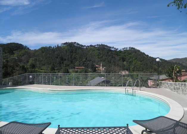 Piscina con vista montagna e sedie a sdraio.