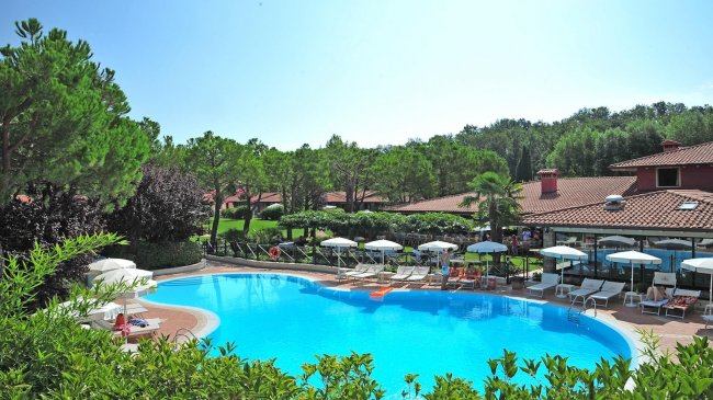 Piscina all'aperto circondata da lettini e ombrelloni bianchi.