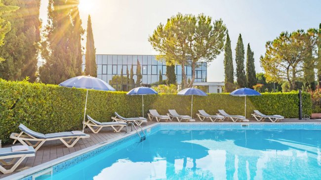 Piscina all'aperto con lettini e ombrelloni blu.