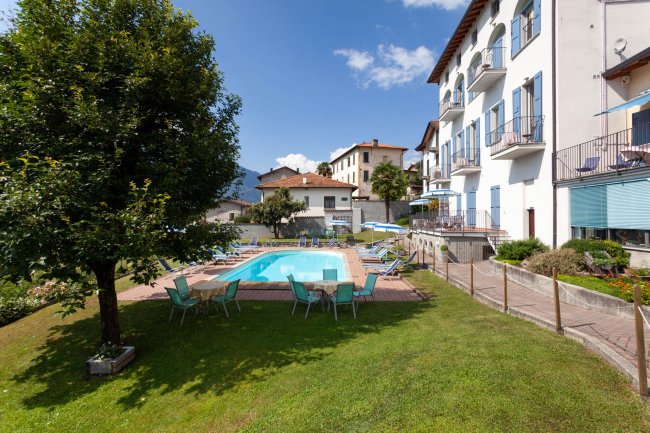 Piscina all'aperto circondata da sedie e un prato.