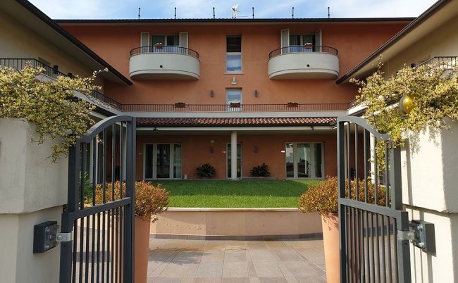 Edificio con giardino e ingresso con cancello.