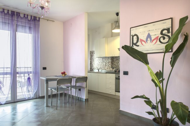 Soggiorno con cucina, pareti rosa, e pianta alta vicino al tavolo.