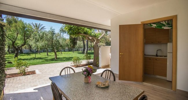 Veranda con tavolo, giardino alberato.