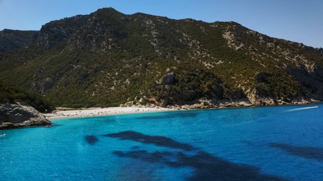 Spiaggia e mare turchese con montagne verdi.