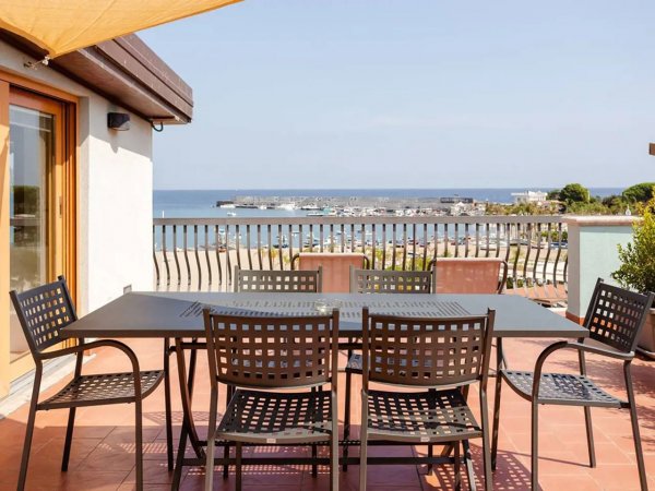 Terrazza con vista mare, tavolo e sedie in metallo.