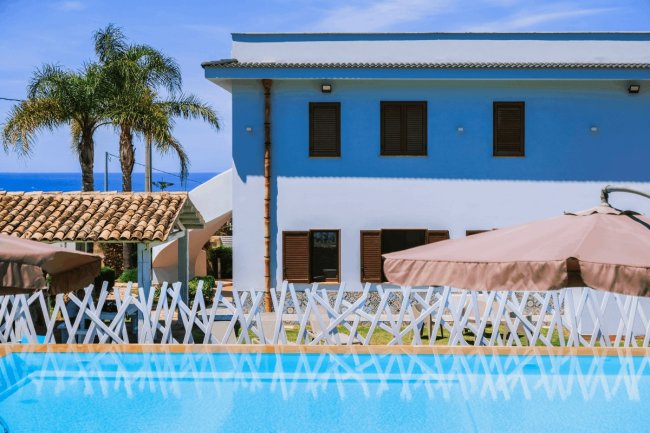 Piscina con vista su edificio blu e palme.