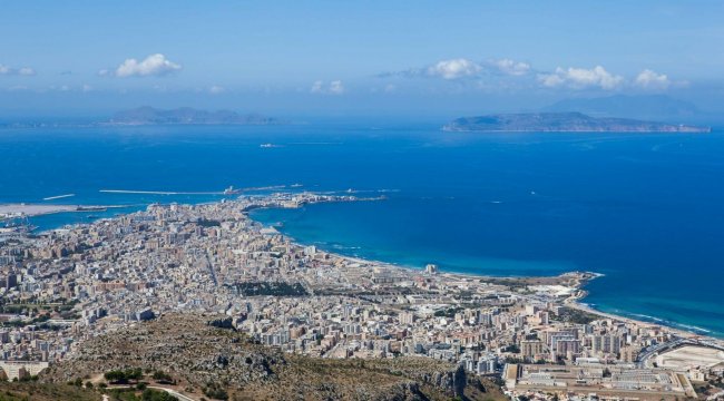 Vista aerea di una città costiera con mare blu e isole in lontananza.